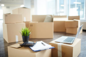 moving boxes sprawled around a bright living room with a laptop clipboard and calculator
