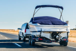suv with boat hitched to back riding down freeway on sunny day extra room self storage